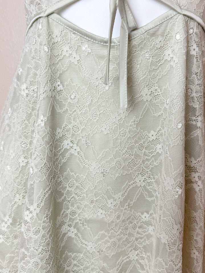 Close-up of a lace dress with thin straps on a plain background