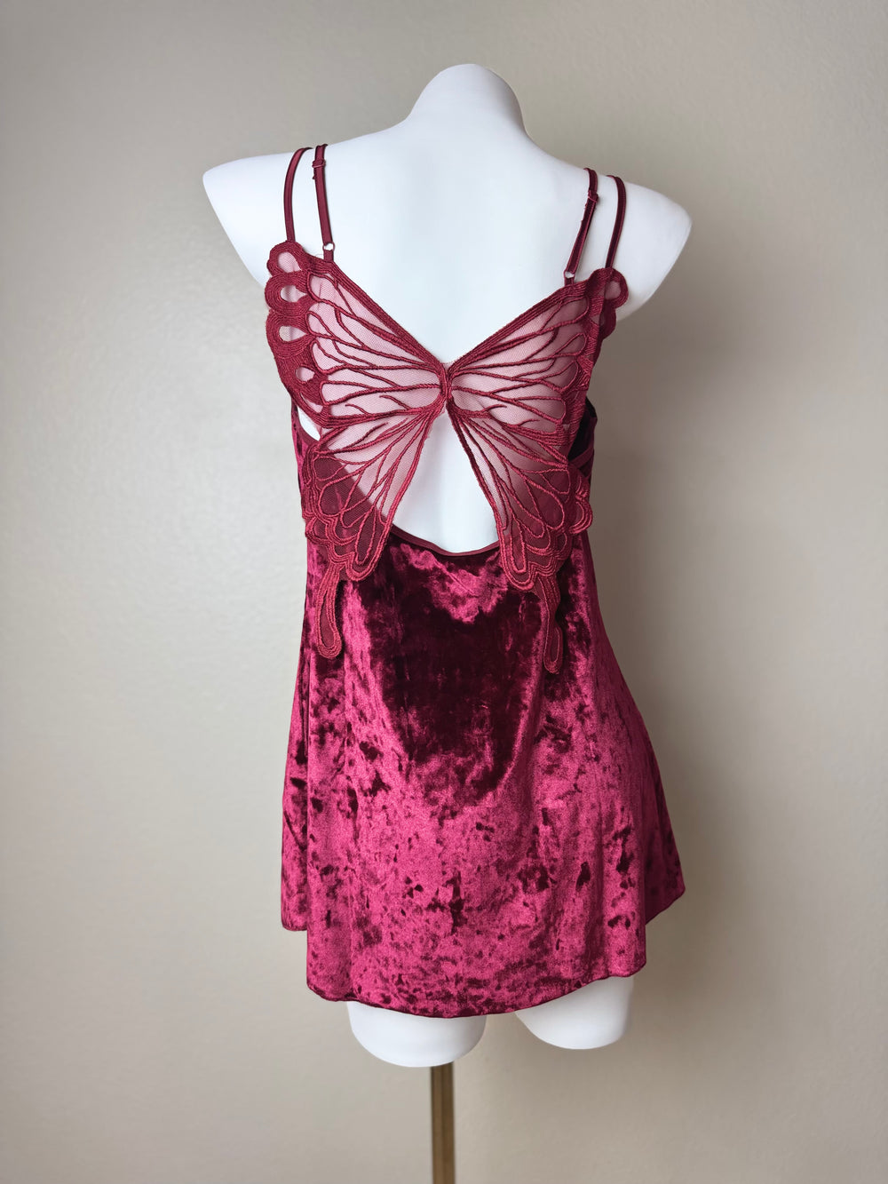back of a red Velvet Butterfly Back Slip dress on a mannequin against a beige background