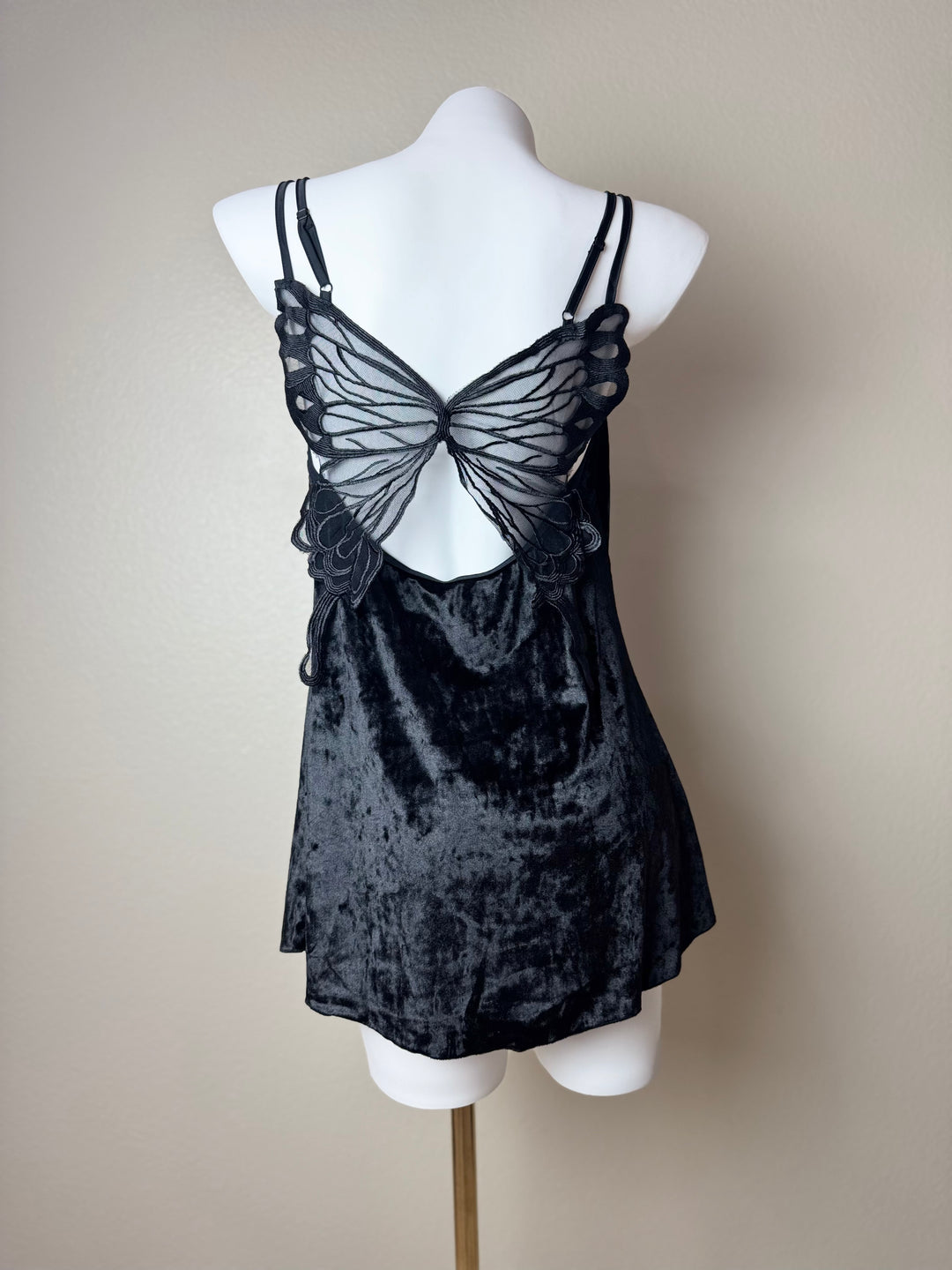 back of a black Velvet Butterfly Back Slip dress on a mannequin against a beige background