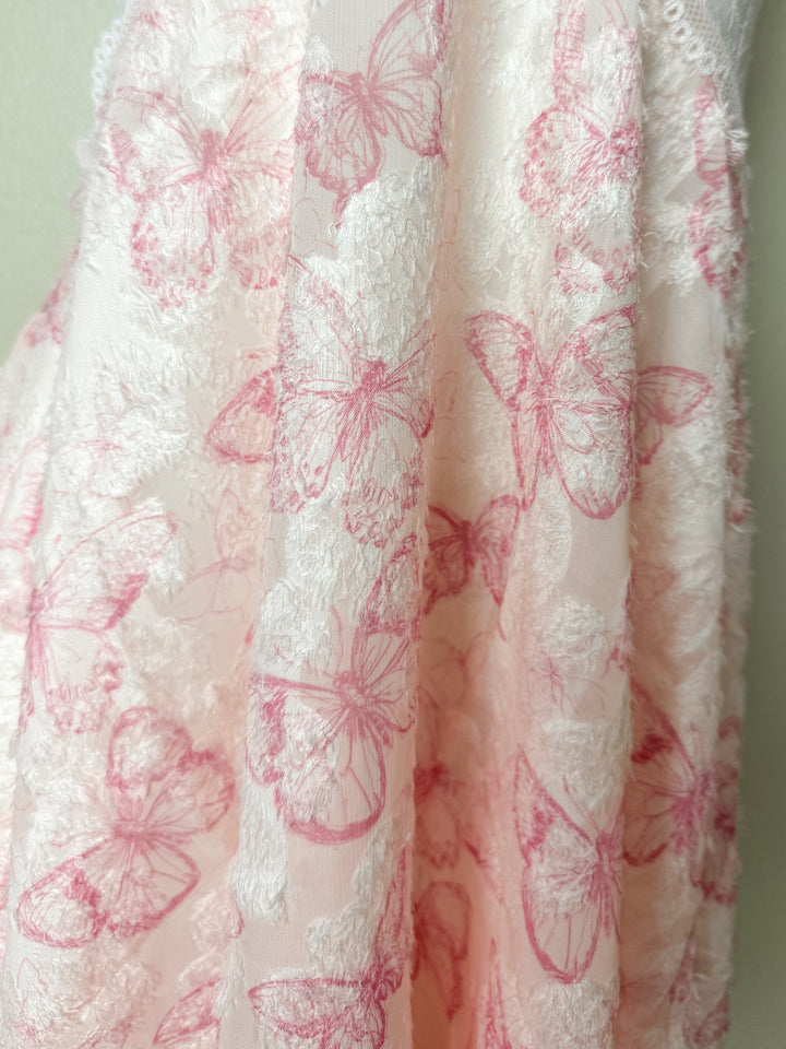 White fabric with pink butterfly patterns on a light green background