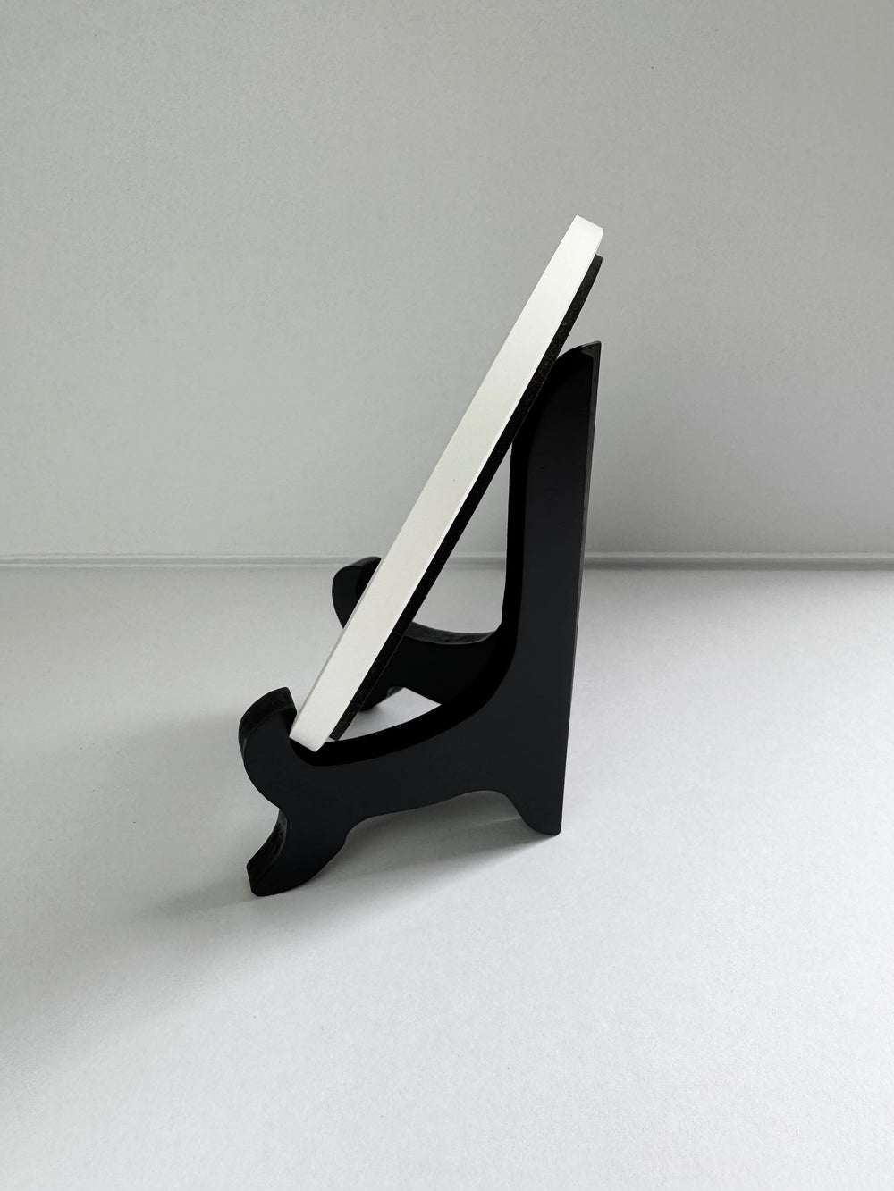 Side of ceramic coaster placing on a stand against a gray background